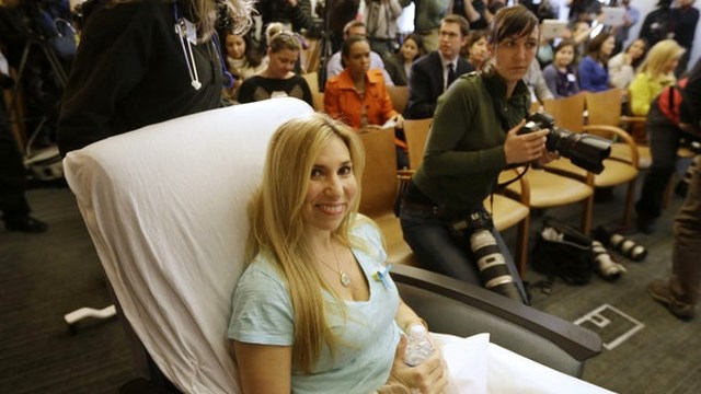 Heather Abbott, of Newport, R.I., is wheeled into a news conference past members of the media, behind, at Brigham and Women's Hospital, in Boston, Thursday, April 25, 2013. Abbott underwent a below the knee amputation during surgery on her left leg following injuries she sustained at the Boston Marathon bombings on April 15. (AP Photo/Steven Senne)